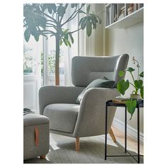 a living room with a chair, ottoman and potted plant