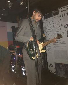 a man standing in front of a microphone while holding a guitar and playing the bass