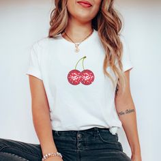 Introducing our Cherry Disco Ball Tee - a sweet and sassy homage to retro glamour and playful vibes. This tee seamlessly fuses the timeless allure of cherries with the glitz of a disco ball, creating a must-have addition to your wardrobe that radiates fun and style. Crafted from soft, comfortable fabric, this tee is perfect for those who appreciate a touch of nostalgia with a modern twist. The design features a vibrant and eye-catching disco ball adorned with whimsical cherries, capturing the essence of carefree nights and energetic dance floors. The playful combination of elements makes it a standout choice for any casual outing or a night of revelry. Machine wash inside out with like colors. Tumble dry on low to medium heat. Do not iron directly on image. Please refer to size chart for r Trendy Crew Neck T-shirt With Cherry Print, Retro Cherry Print T-shirt For Summer, Sweet White Crew Neck Top, Red Cherry Print Short Sleeve Top, Red Cotton T-shirt With Cherry Print, Red Cherry Print Graphic Tee, Y2k Cherry Print Summer T-shirt, White Y2k Tops With Cherry Print, Y2k Style Cherry Print Summer T-shirt