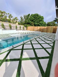 an outdoor swimming pool with artificial grass in the ground and fenced in area next to it