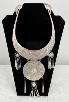 "Vintage Thailand Collar Necklace/Etched Floral/Silver Platted/12\" L x 5 1/2\". Stunning Vintage Hmong Miao Torque silver necklace . Silver plate brass ceremonial Torque Necklace with fringe & bells. Hand engraved with botanical scroll motif & elongated links. Hangs and moves beautifully, the bib fits with hook closure. Good vintage condition, the few areas that are showing age are some of the silver around the neck area is faded and the two top dangling flowers are pushed in. Please see pictures for full details. Miao silver is not pure silver, but an alloy of silver, copper and nickel. It's a traditional material for making jewelry by craftsmen of Miao Hmong ethnic tribe. Necklace hangs: 12\" long x 5 1/2\" wide" Artisan Silver Etched Necklace, Artisan Silver Necklace For Festivals, Artisan Silver Necklace For Festival, Adjustable Silver Ceremonial Necklace, Ceremonial Silver Jewelry With Large Pendant, Silver Metal Necklace For Ceremonial Occasions, Silver Adjustable Necklaces For Ceremonial Occasions, Silver Adjustable Necklace For Ceremonial Use, Adjustable Silver Necklace For Ceremonial Use