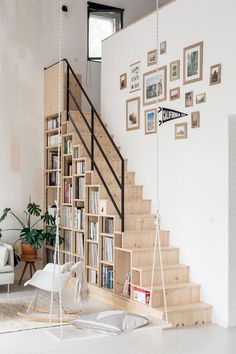 a room with some bookshelves and pictures on the wall above it, along with a swing chair