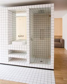 an empty bathroom with white tile walls and wood flooring is seen in this image