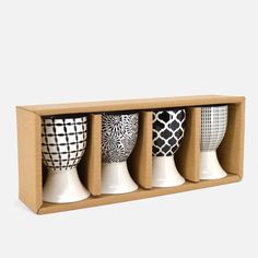 four vases in a cardboard box with black and white designs on the front one is empty