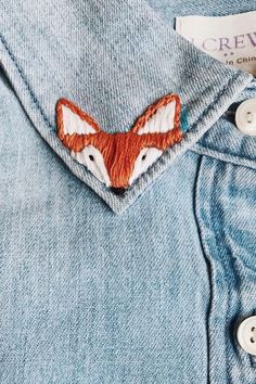 a close up of a shirt with a fox embroidered on the front and chest pocket