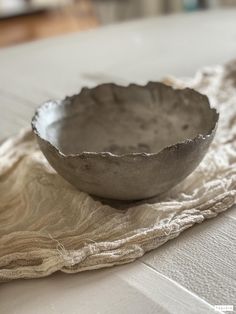 a silver bowl sitting on top of a table next to a white cloth covered napkin