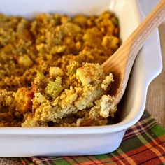 a casserole dish with stuffing in it and a wooden spoon on the side