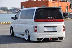 the rear end of a white van parked in front of a body of water