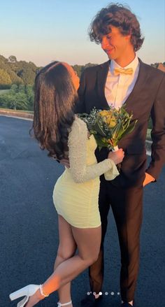 a man in a tuxedo standing next to a woman wearing a yellow dress