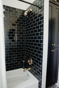 a bathroom with black and white tiles on the walls, shower head, and bathtub