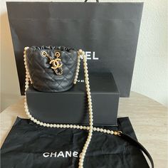 New In The Box This Is An Authentic Chanel Calfskin Quilted Pearl Mini About Pearls Drawstring Bucket Bag In Black. This Crossbody Bag Features A Resin Pearl Shoulder Strap With A Black Leather Shoulder Pad And A Leather Threaded Aged Gold Chain Drawstring. This Opens To A Red Fabric Interior. Base Length: 4.25 In Height: 4.5 In Width: 4.5 In Drop: 23 In Receipt Upon Requested Designer Top Handle Bucket Bag As Gift, Designer Bucket Bag With Detachable Handle As Gift, Luxury Pouch Evening Bag With Pearl Handle, Luxury Evening Bag With Pearl Handle, Luxury Bucket-shaped Evening Bag For Formal Occasions, Luxury Bucket Evening Bag For Formal Occasions, Luxury Bucket Style Evening Bag For Formal Occasions, Luxury Bucket Style Formal Evening Bag, Luxury Pouch Shoulder Bag With Pearl Handle