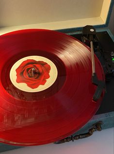 an old record player with a red rose on it's side, in a case