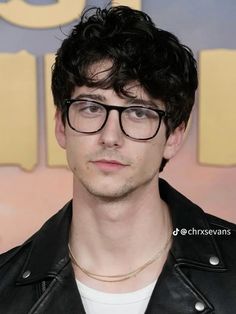 a man wearing glasses and a leather jacket