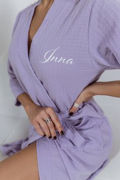 a woman in a purple robe posing for the camera with her hand on her hip