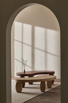 a wooden bench sitting in the middle of a room next to a vase with flowers