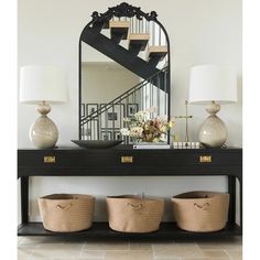 a console table with three baskets under a mirror