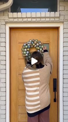 a woman standing in front of a door with a wreath on it's head