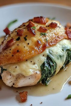 a white plate topped with chicken covered in cheese and spinach