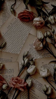 some flowers are laying on top of an old book with pages scattered around them and the paper is torn off