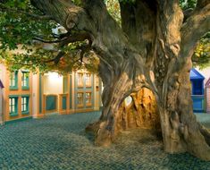 a large tree in the middle of a room with blue and green tiles on the floor