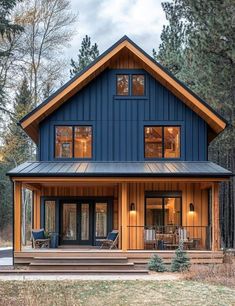 a blue house in the woods with lots of windows