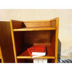 three books are stacked on top of each other in a wooden bookcase next to a wall