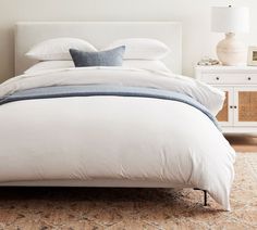 a bed with white sheets and blue pillows