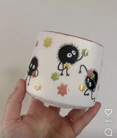 a hand holding up a cup decorated with black and white monsters on it's sides