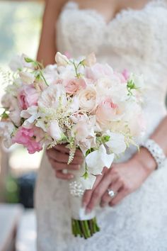 a bride holding a bouquet of white and pink flowers