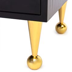 a black and gold dresser with two golden knobs on the bottom, one drawer open