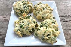 four biscuits with spinach and cheese are on a white plate, ready to be eaten