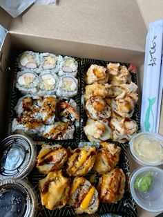 an open box filled with different types of sushi and other foods on top of it