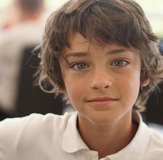 a young boy with freckled hair and blue eyes is looking at the camera