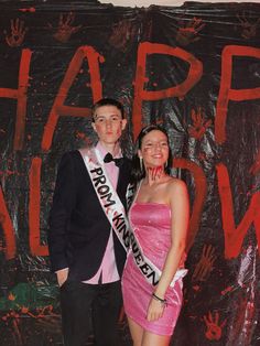 a young man and woman posing for a photo in front of a happy halloween backdrop