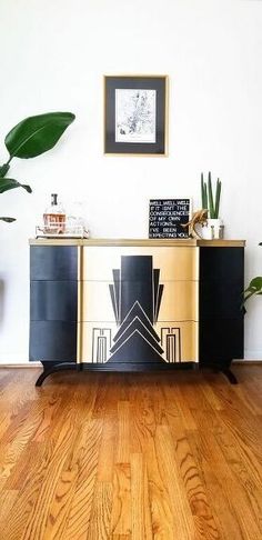 a black and gold sideboard sitting on top of a wooden floor next to potted plants