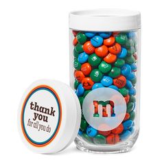 a jar filled with lots of colorful m and m candies next to a white container that says thank you for all you do