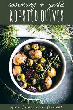 rosemary and garlic roasted olives in a white bowl on a table with pine branches