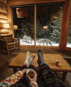 two people sitting in front of a window with their feet on a table