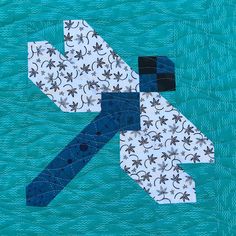 a piece of quilted fabric with blue and white designs on it, in the shape of an arrow