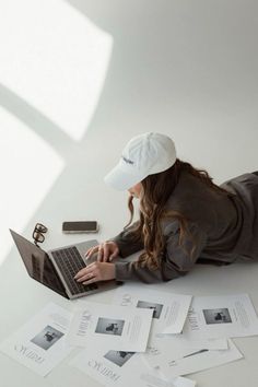 a woman is laying on the floor with her laptop in front of her and papers all around her