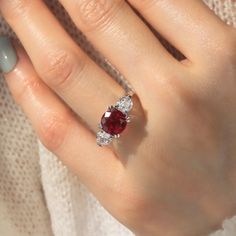 a woman's hand with a ring on it and a red stone in the middle