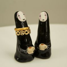 two black cats with gold rings on their heads are standing next to each other in front of a white background