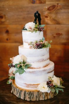 a white wedding cake with flowers and a couple figurine on the top tier