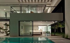 a modern house with an indoor swimming pool and glass doors leading to the upper level