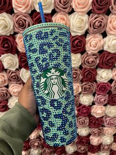 someone holding up a starbucks cup in front of roses that have been placed on the wall