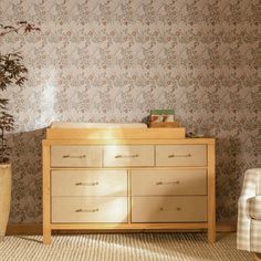 a baby crib in the corner of a room next to a chair and potted plant