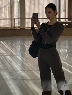 a woman taking a selfie with her cell phone in the middle of an empty room