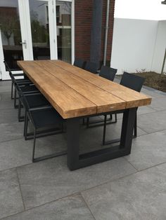 a wooden table sitting on top of a patio next to a brick building with glass doors