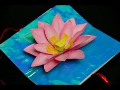 a pink flower sitting on top of a blue and yellow book cover with red string