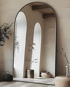 a mirror sitting on top of a wooden floor next to a vase and potted plant